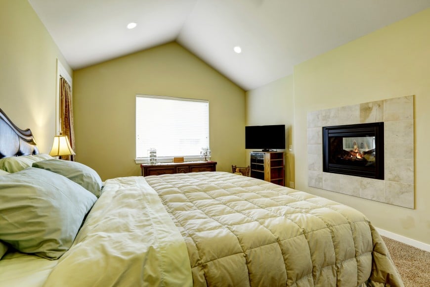 this bedroom has a beautiful vaulted ceiling and an in-wall fireplace.